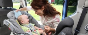 Child Seat Mother secures baby in child car seat
